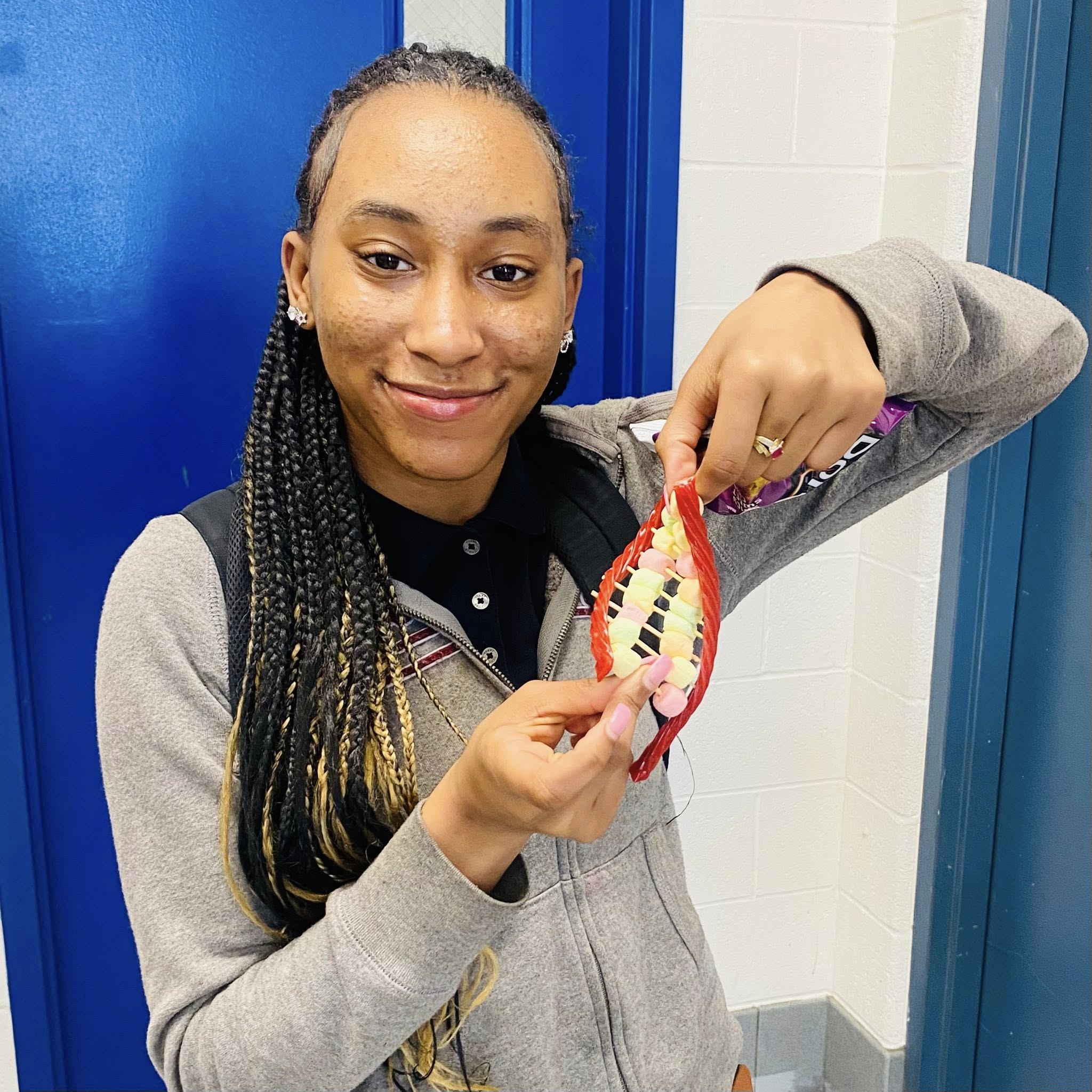 A girl holding a miniature DNA strand made of Twizzlers, mini marshmallows, and toothpicks.